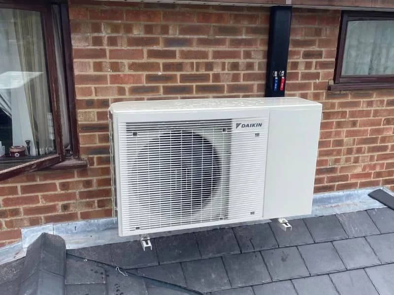 A Daikin outdoor unit wall mounted above a slate roof