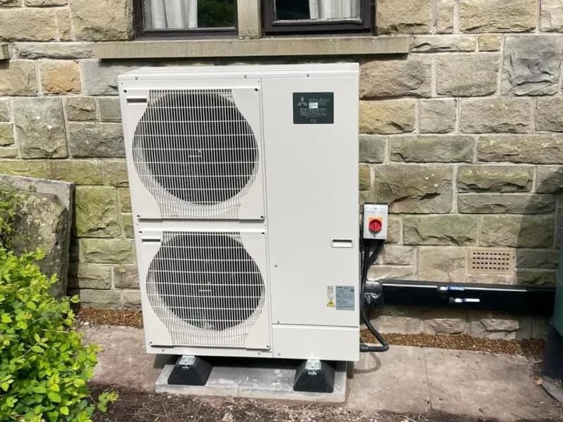 A twin-fan Mitsubishi Electric Zubadan air source heat pump against a Yorkshire stone house