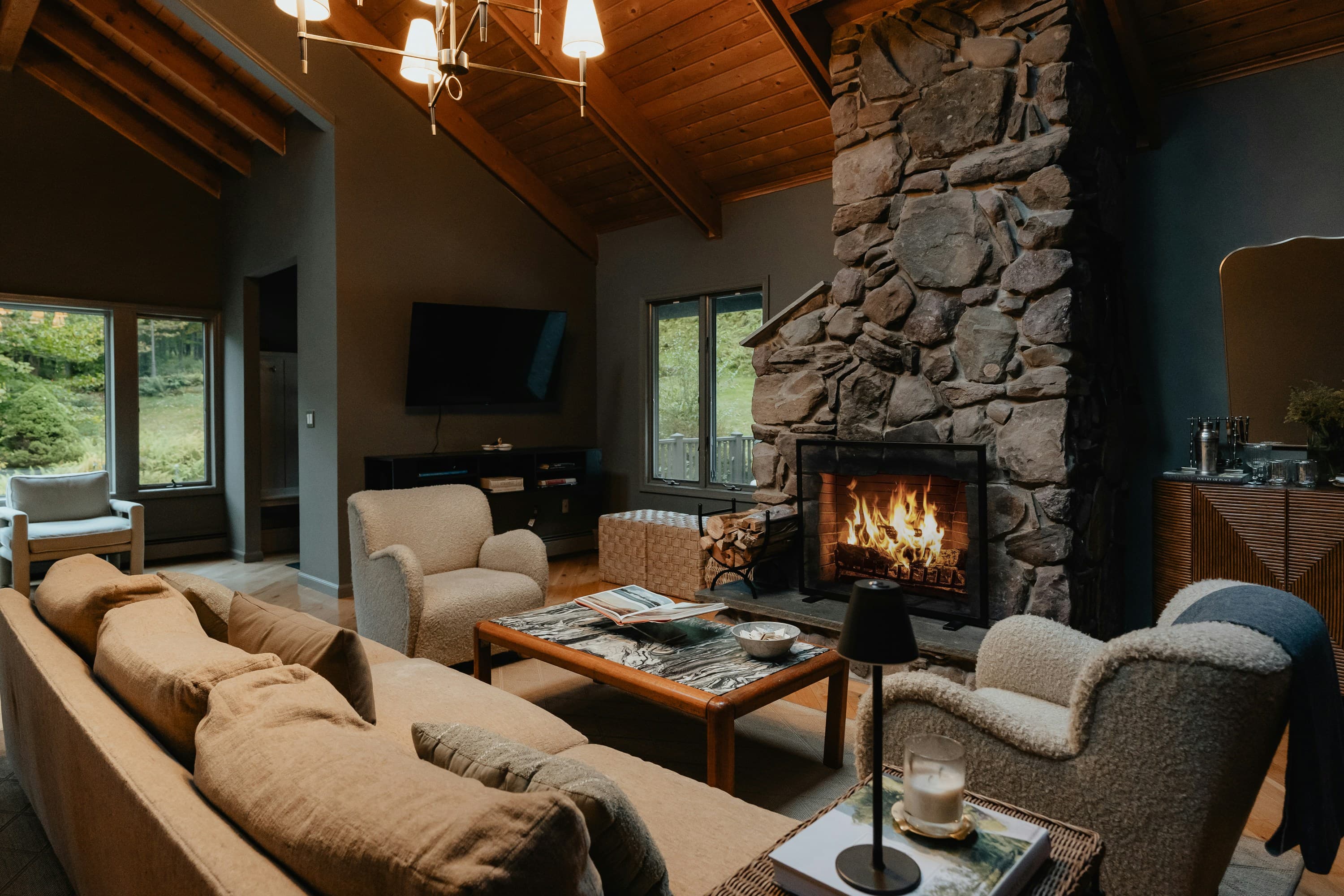 A living room in the evening with a wood burner lit and lamps on